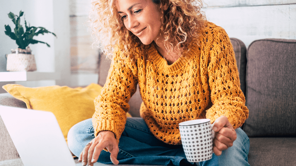 woman holding coffee and using laptop