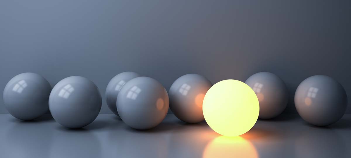 Eight gray marbles on a table with one bright and illuminated