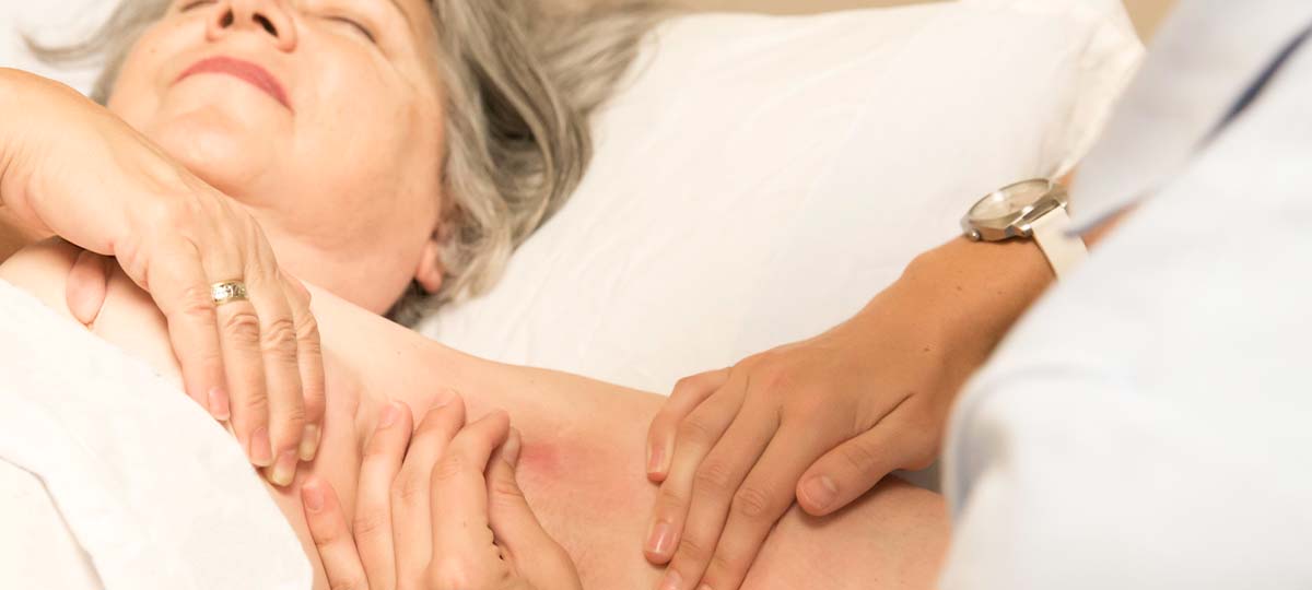 Older person laying supine with massage therapist massaging top arm
