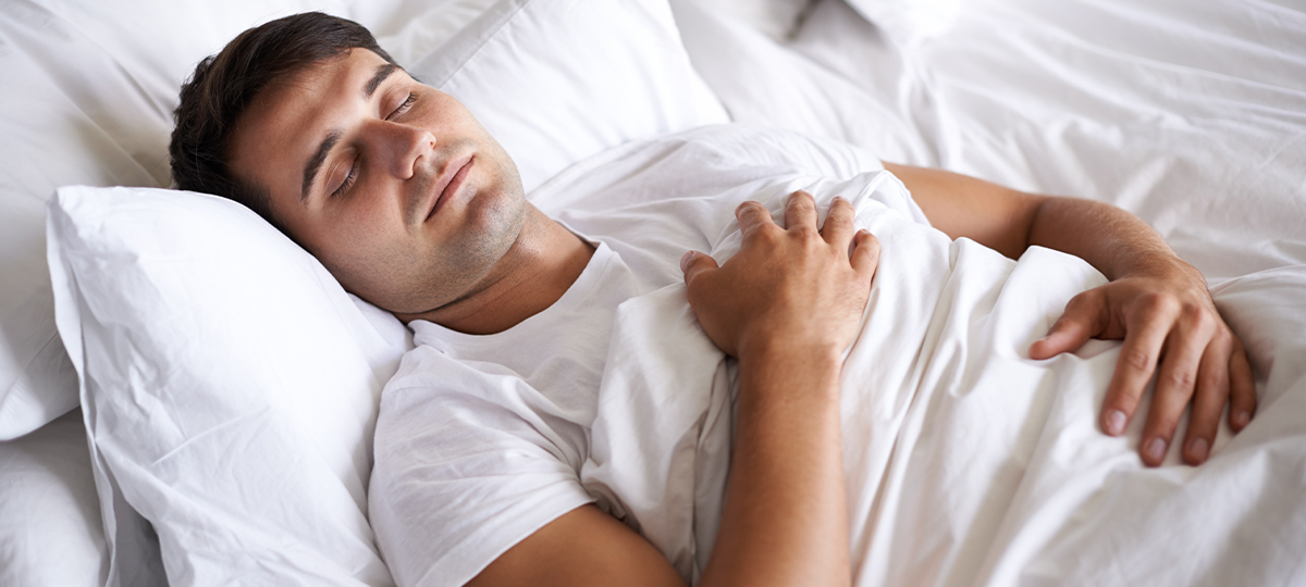 Person lying in bed hands on chest asleep