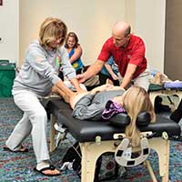 massage students learning massage technique from instructor