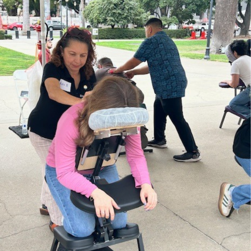 an image of a woman receiving a massage on a chair outside a capitol building.