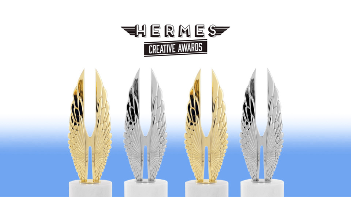 An image of four trophies, gold and platinum, with the words "Hermes Creative Awards" in black text above. The background is white with blue shading rising from the bottom.