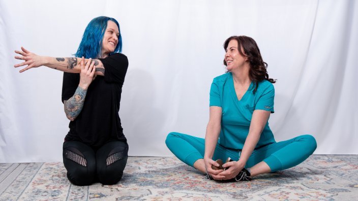 an image of two female massage therapists stretching together.
