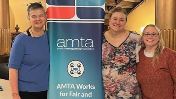 an image of three people smiling and standing next to an AMTA Advocacy Day sign.