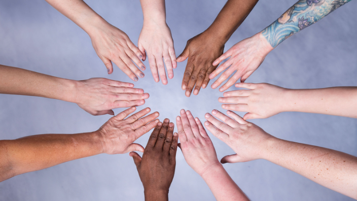 Diverse hands make a circle.