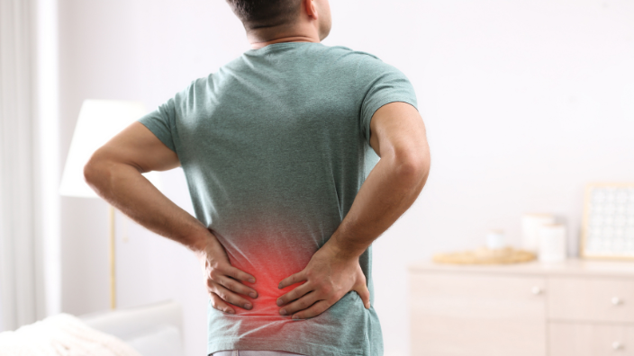 an image of a man holding his back in pain.