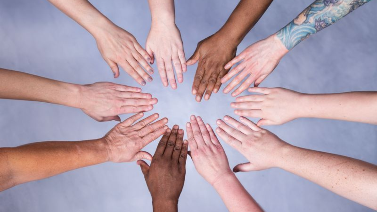 an image of a group of massage therapist's hands forming a circle.