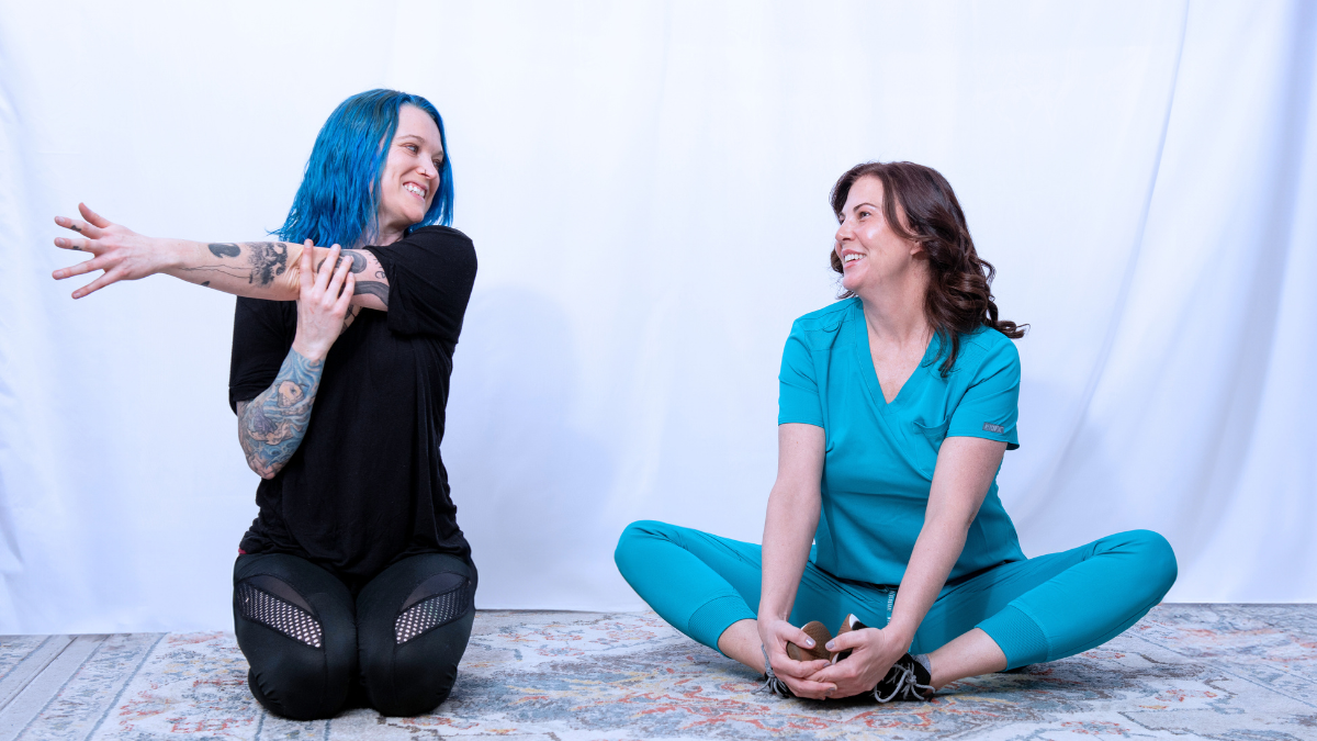 an image of two female massage therapists stretching next to each other.