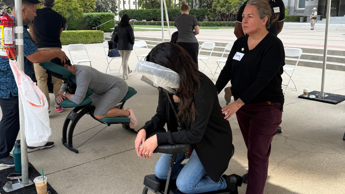 an image of people receiving chair massage outside a government building.