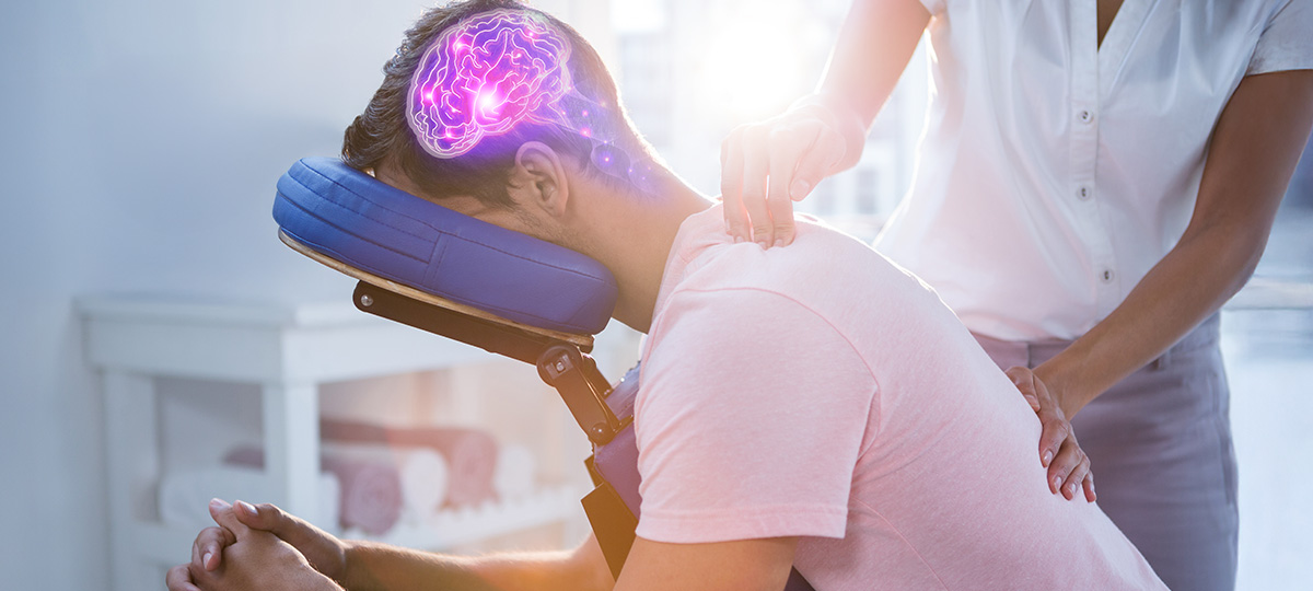 an image of someone receiving a chair massage, a graphic showing the anatomical brain is layered over their head, showing holistic care.