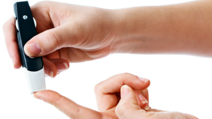 close up of hands performing diabetes finger stick test