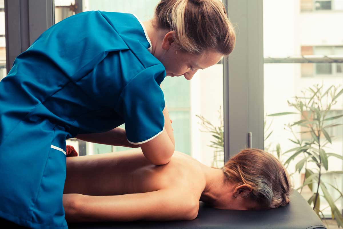 female massage therapist massaging client