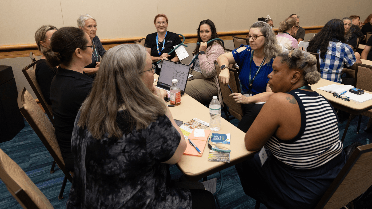 Group of teachers sit and talk around a table