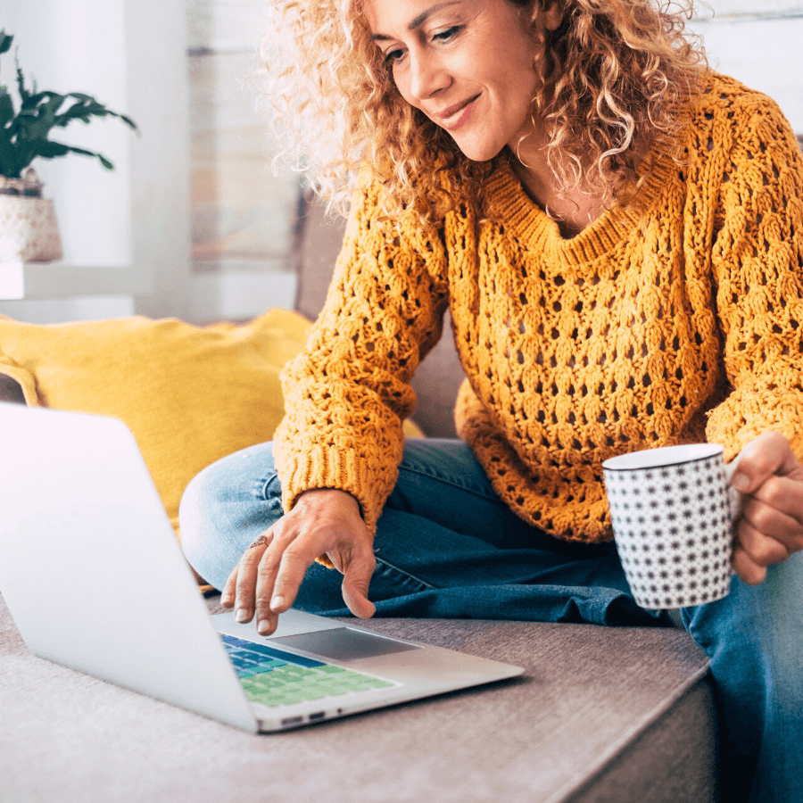 woman holding coffee and using a laptop