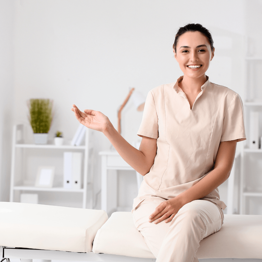 Woman sitting a massage table, smiling and waving