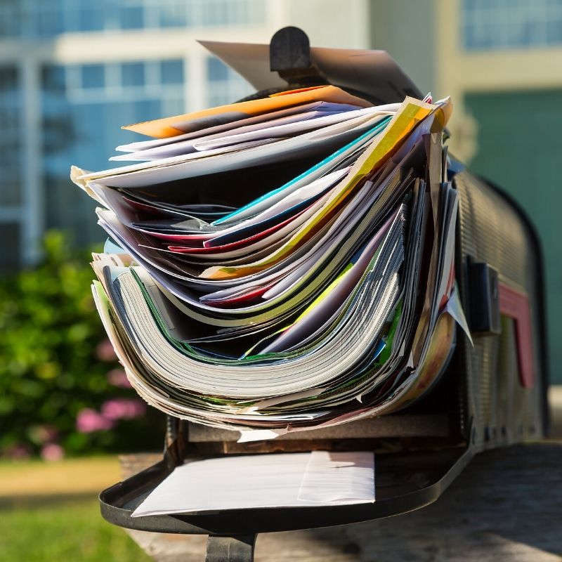 mailbox in front of house overflowing with mail