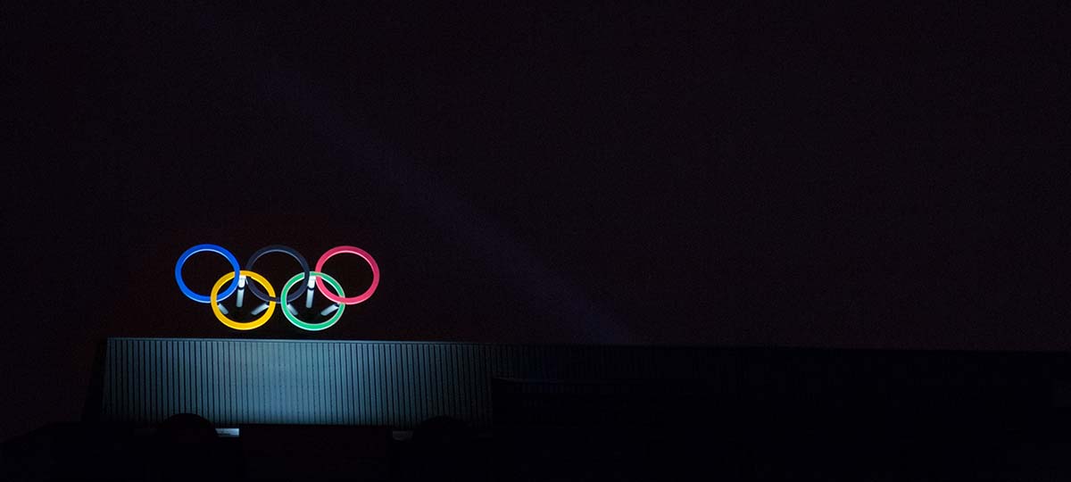 Dark with Olympic Rings on building being spotlighted