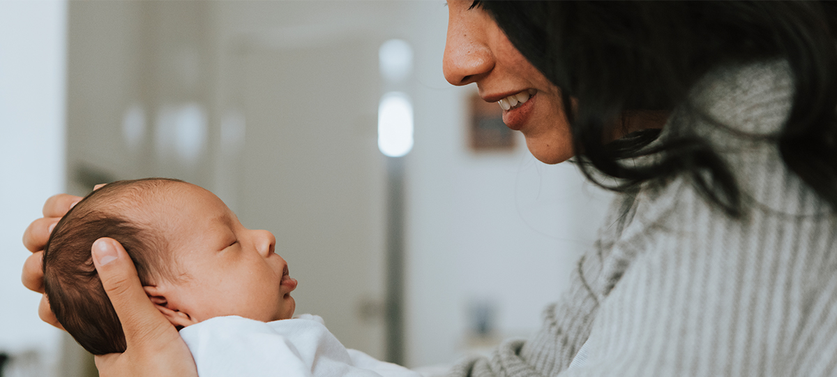 Person holding sleeping infant fact-to-face smiling